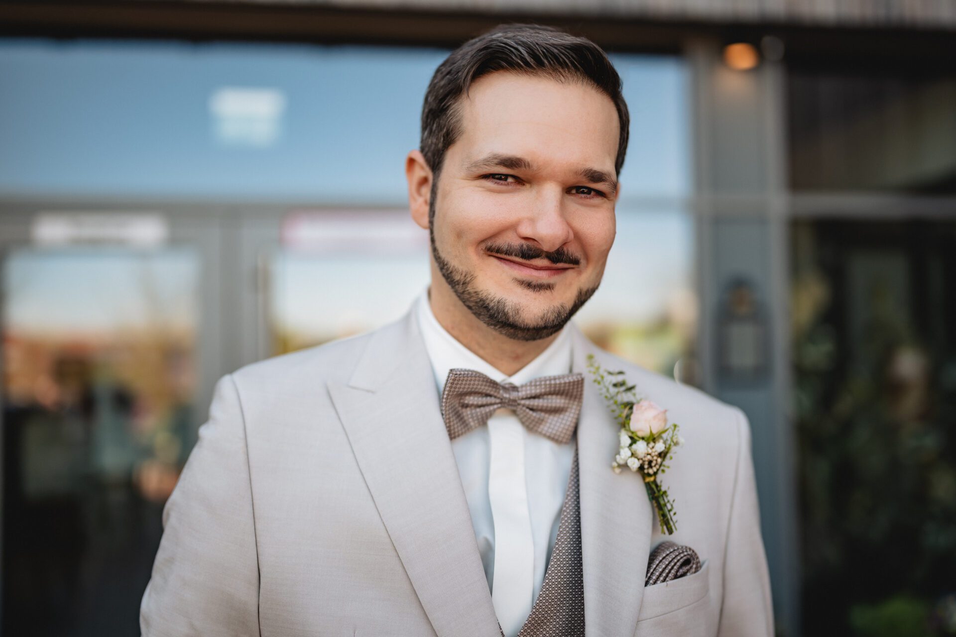 Eine Nahaufnahme eines farbenfrohen Brautstraußes mit weißen, rosafarbenen und pfirsichfarbenen Rosen, lila Distelblüten und grünem Laub, wunderschön eingefangen von einem Hochzeitsfotografen in München. Die perfekte Inspiration für Ihre Hochzeitsfotos. Hochzeitsfotos_Hochzeitsfotograf_München