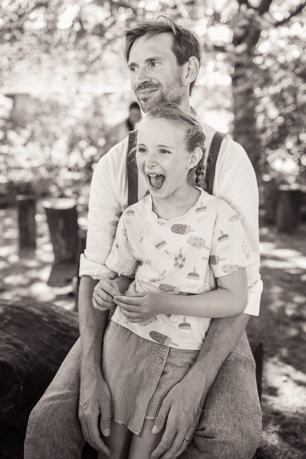 Eine Braut und ein Bräutigam stehen in einer Türöffnung, umarmen sich und lächeln sich an. Aufgenommen von einem Hochzeitsfotografen in München, hält die Braut einen Blumenstrauß, und beide sind in Hochzeitskleidung, schön eingerahmt durch ein dekoratives Tor im Freien. Hochzeitsfotos_Hochzeitsfotograf_München