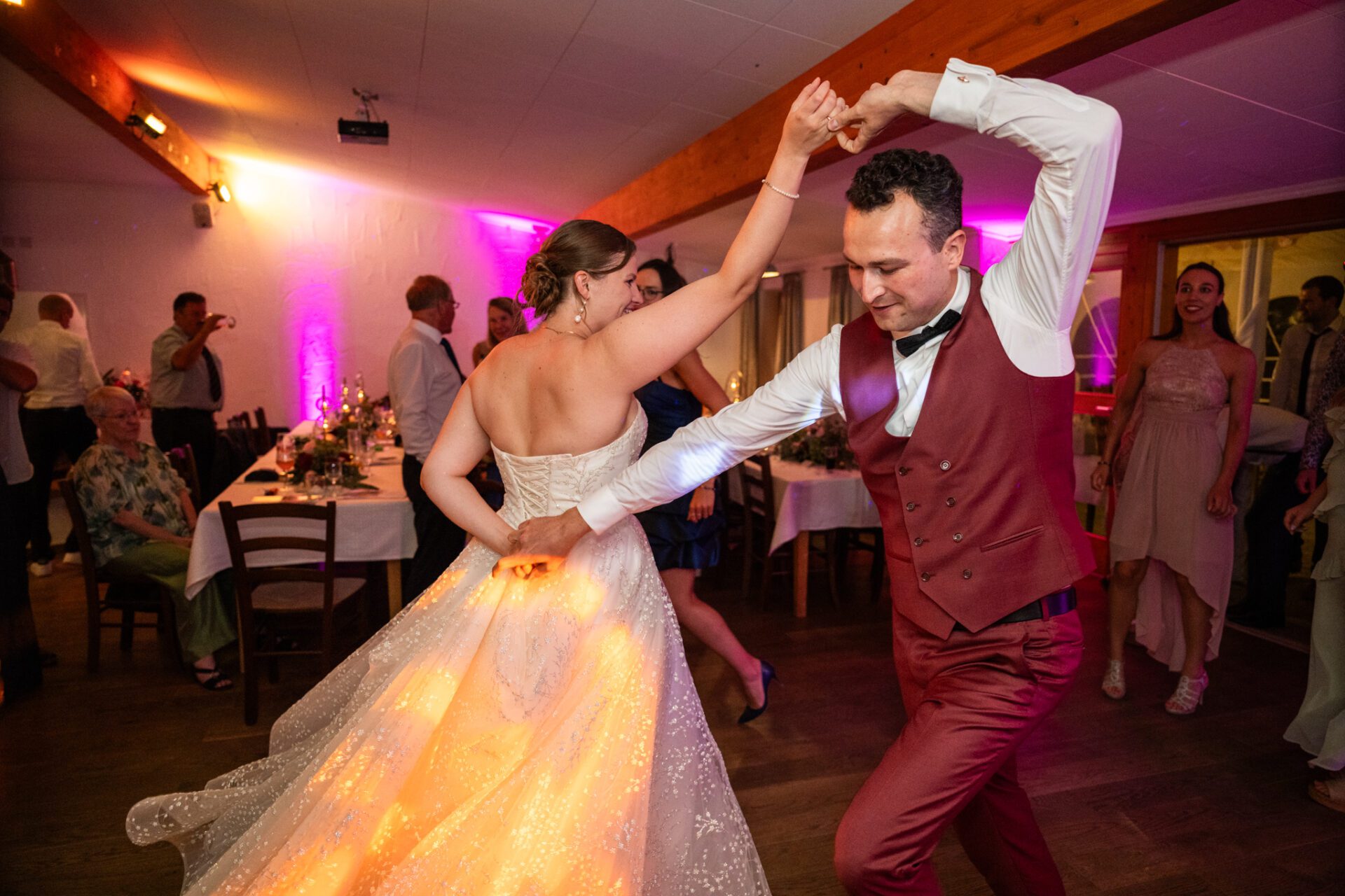 Eine Braut und ein Bräutigam stehen in einer Türöffnung, umarmen sich und lächeln sich an. Aufgenommen von einem Hochzeitsfotografen in München, hält die Braut einen Blumenstrauß, und beide sind in Hochzeitskleidung, schön eingerahmt durch ein dekoratives Tor im Freien. Hochzeitsfotos_Hochzeitsfotograf_München